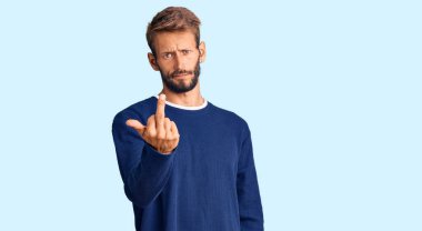 Handsome blond man with beard wearing casual sweater showing middle finger, impolite and rude fuck off expression 