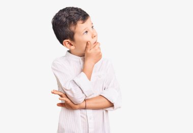 Zarif tişört giyen sevimli sarışın bir çocuk bir soru hakkında endişeleniyor, endişeli ve gergin. 