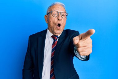 Üst düzey beyaz takım elbiseli ve kravatlı bir adam parmağıyla işaret ederek şaşırdı, ağzı açık hayrete düştü, ön tarafta bir şey vardı. 