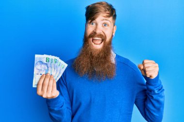 Genç İrlandalı kızıl saçlı adam Güney Afrika 'yı elinde tutuyor. 100 rand' lık banknotlar gururla bağırıyor, zaferi kutluyor ve başarıyı kollarını kaldırarak kutluyor. 