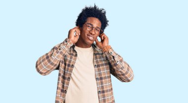 Gürültülü müzik sesi için Afro saçlı, gözlüklü, kulaklarını parmaklarıyla kapatan yakışıklı Afro-Amerikalı bir adam. sağır kavramı. 