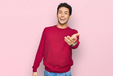 Gündelik kıyafetler giyen genç yakışıklı adam dostça bir selamlama ve hoş geldin hediyesi olarak el sıkışmayı sunuyor. başarılı iş. 