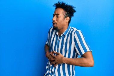 Sakallı, sıradan çizgili tişörtlü, midesi bulanan, acı verici bir hastalık yüzünden hasta olan Afro-Amerikalı genç bir adam. Ağrı kavramı. 