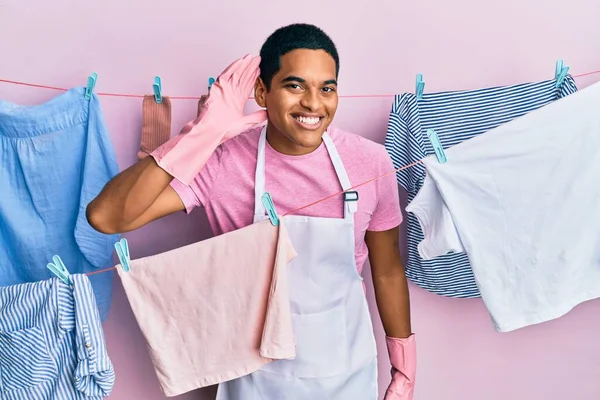 Jovem Hispânico Bonito Vestindo Avental Mais Limpo Segurando Roupas Varal — Fotografia de Stock