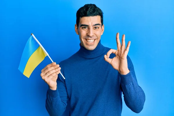 Bonito Homem Hispânico Vestindo Bandeira Ucraniana Fazendo Sinal Com Dedos — Fotografia de Stock