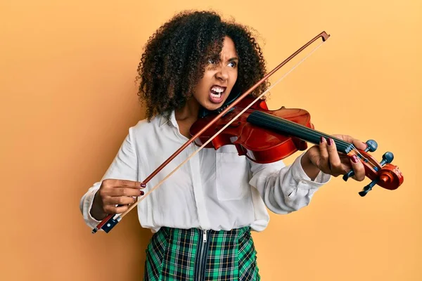 古典的なバイオリンを演奏するアフロの髪を持つ美しいアフリカ系アメリカ人の女性怒りと怒りで叫んで フラストレーションと激怒叫んでいる 怒りと攻撃的な考え方 — ストック写真