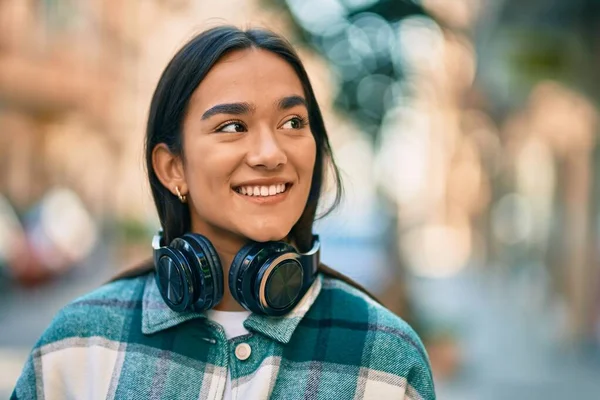 若いですラテン語の女の子笑顔幸せな使用ヘッドフォンで街 — ストック写真