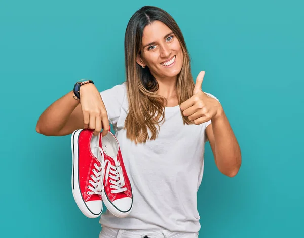 Mujer Joven Sosteniendo Zapatos Casuales Rojos Sonriendo Feliz Positivo Pulgar —  Fotos de Stock