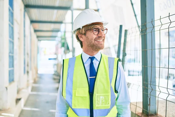 Business architect man wearing hardhat standing outdoors of a building project wearing reflective vest