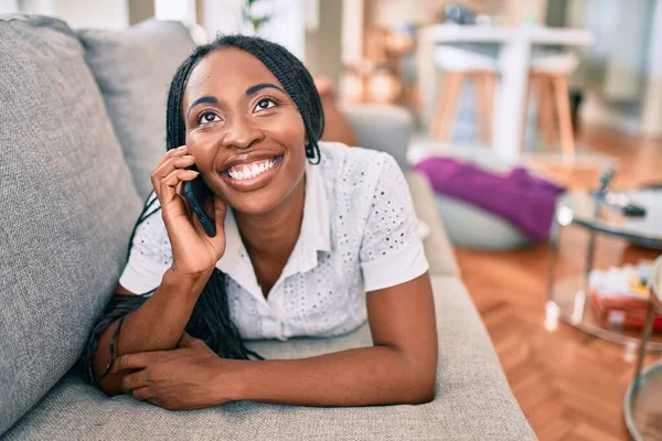Jovem Afro Americana Sorrindo Feliz Usando Smartphone Deitado Sofá Casa — Fotografia de Stock