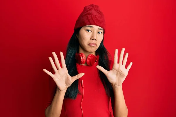 若い中国の女性は ヘッドフォンを使用して音楽に耳を傾け 恐怖表現を恐れて手でジェスチャーを停止し ショックで叫んで恐れている パニックの概念 — ストック写真
