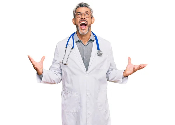 医者の制服を着た中年の白髪の男が狂気と怒鳴り声を上げ積極的な表情と腕を上げて叫んでいます フラストレーションコンセプト — ストック写真