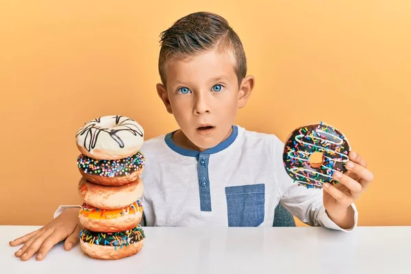 Bedårande Kaukasiska Unge Äta Munkar Till Frukost Chockansikte Ser Skeptisk — Stockfoto