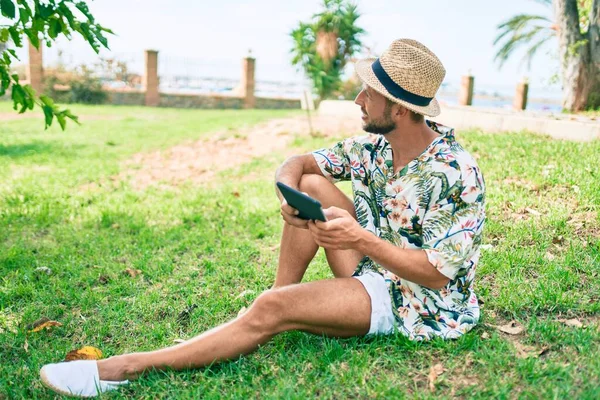 Caucasiano Bonito Homem Sorrindo Feliz Usando Touchpad Dispositivo Sentado Grama — Fotografia de Stock