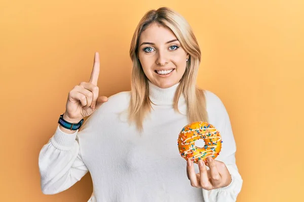 Joven Mujer Caucásica Sosteniendo Donut Sonriendo Con Una Idea Pregunta —  Fotos de Stock