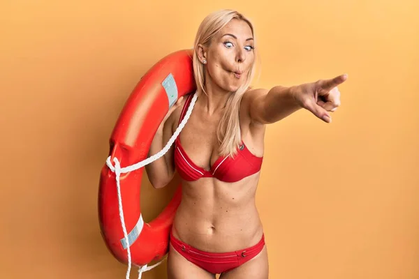 Young Blonde Woman Wearing Bikini Holding Lifeguard Float Pointing Finger — Stock Photo, Image