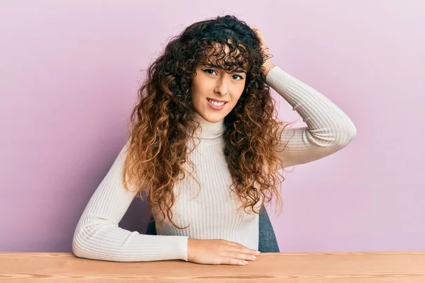 Gündelik giysiler giyen genç İspanyol kız masada oturuyor ve soru sormayı merak ediyor. Şüpheyle kararsız, kafa kafaya düşünerek. Düşünceli kavram. 