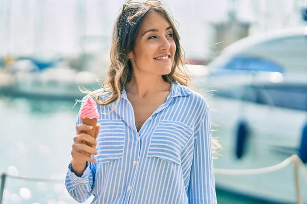 Genç İspanyol kadın gülümseyerek limanda dondurma yiyor..