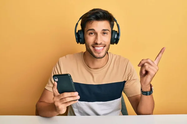 Young Handsome Man Using Smartphone Wearing Headphones Smiling Happy Pointing — Stock Photo, Image