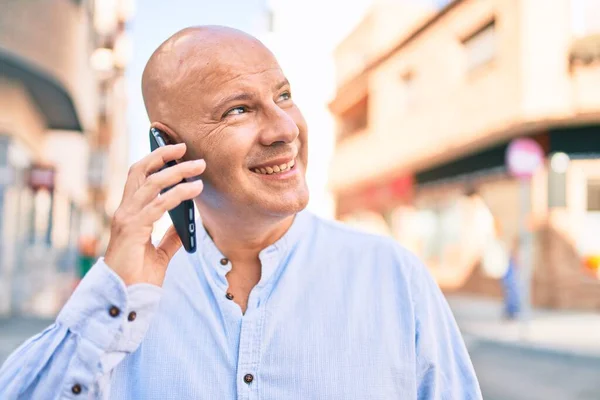 Middle age bald man smiling happy talking on the smartphone at the city.