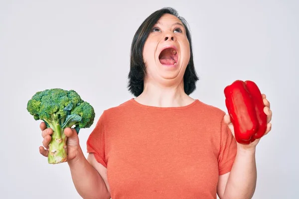 Mulher Morena Com Síndrome Segurando Brócolis Pimenta Vermelha Irritado Louco — Fotografia de Stock