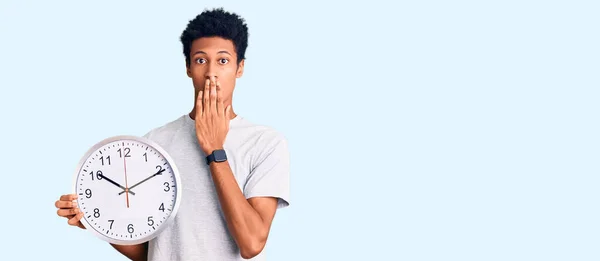 手で口を覆う大きな時計を持っている若いアフリカ系アメリカ人男性は ショックを受け 間違いを恐れています 驚きの表情 — ストック写真