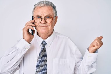 Senior grey-haired man wearing business clothes having conversation talking on the smartphone screaming proud, celebrating victory and success very excited with raised arm 