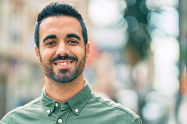 Genç İspanyol adam gülümseyerek şehirde mutlu mesut dikiliyor..