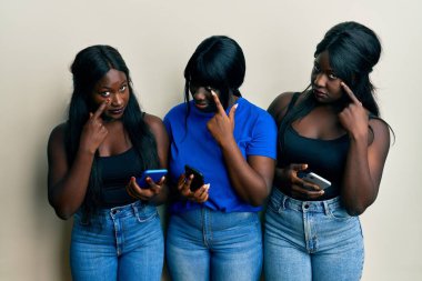 Üç Afro-Amerikalı genç arkadaş akıllı telefon kullanarak senin jestini ve şüpheli ifadeni izliyorlar. 