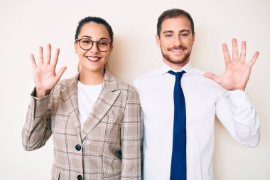 İş kıyafetleri giymiş güzel bir çift on numarayı gösterip işaret ederken kendinden emin ve mutlu bir şekilde gülümsüyor.. 
