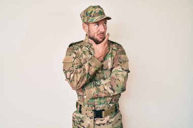 Kamuflaj üniforması giyen genç beyaz bir adam bir soru hakkında endişeli ve gergin bir şekilde düşünüyor. 