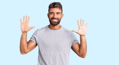 Gündelik kıyafetler giyen genç İspanyol adam on numarayı gösterip işaret ederken kendinden emin ve mutlu bir şekilde gülümsüyor.. 