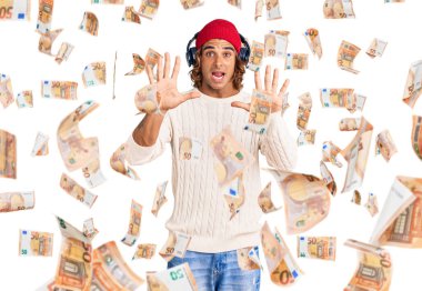 Kulaklık kullanarak müzik dinleyen genç İspanyol adam korku ifadesinden korkmuş ve dehşete düşmüş. El hareketlerini durdur, şok içinde bağır. panik konsepti.