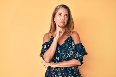 Orta yaşlı İspanyol kadın, gündelik kıyafetler giyiyor ciddi yüz ifadesi, eli çeneli soruyu düşünüyor, kafa karıştırıcı bir fikir. 