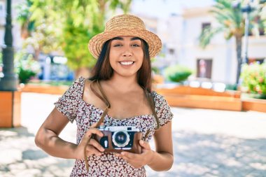Şehrin caddesinde gezen eski model kamera kullanan genç Latin kadın..