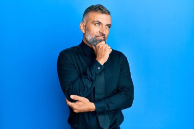 Middle age handsome man wearing business shirt and tie with hand on chin thinking about question, pensive expression. smiling with thoughtful face. doubt concept. 