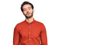 Günlük kıyafetler giyen genç İspanyol adam yüzünde ciddi bir ifadeyle rahatlamış. Basit ve doğal bir şekilde kameraya bakıyorsun.. 