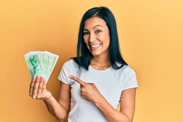 stock image Beautiful hispanic woman holding 5 singapore dollars banknotes smiling happy pointing with hand and finger 