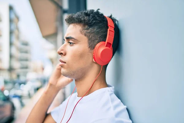 市内でヘッドフォンを使用して音楽を聴く真剣な表情の若いラテン人 — ストック写真
