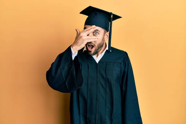 Young Hispanic Man Wearing Graduation Cap Ceremony Robe Peeking Shock — Φωτογραφία Αρχείου