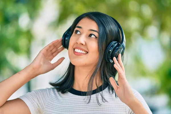若いヒスパニック系の女性は 市内でヘッドフォンを使用して音楽を聞いて幸せな笑顔 — ストック写真