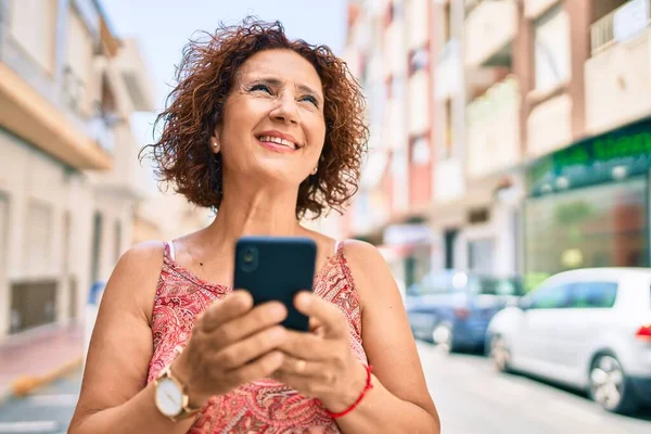 中世の女性は街の通りを歩いてスマートフォンを使用して幸せな笑顔 — ストック写真