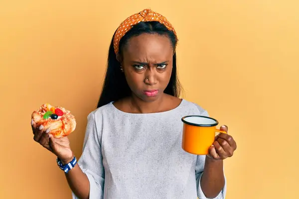 Mujer Africana Joven Bebiendo Café Comiendo Pastelería Escéptico Nervioso Frunciendo — Foto de Stock