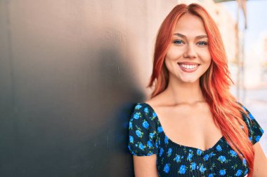 Genç kızıl saçlı kız gülümsüyor Mutlu bir şekilde yürüyor şehrin caddesinde.