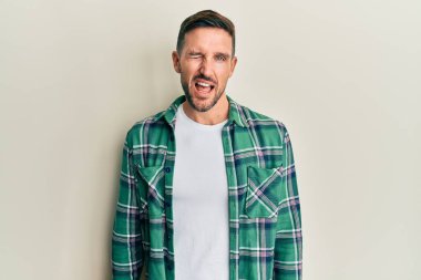 Sakallı, sıradan kıyafetler giyen, kameraya seksi bir ifadeyle bakan, neşeli ve mutlu yüzlü yakışıklı bir adam.. 