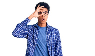 Sıradan kıyafetler ve gözlük takan Afro-Amerikan genç adam şaşırmış yüz ifadesiyle şaşırmış ve parmaklarından içeri bakıyordu. İnançsız ifade. 