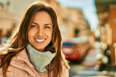 Genç İspanyol kadın gülümseyerek şehirde mutlu mesut dikiliyor..