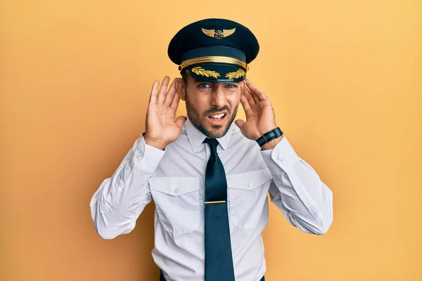 Handsome Hispanic Man Wearing Airplane Pilot Uniform Trying Hear Both — Foto Stock