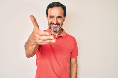 Orta yaşlı İspanyol bir adam günlük giysiler içinde gülümseyerek dostça el sıkışarak selamlama ve hoş geldin diyor. başarılı iş. 