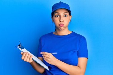 Kurye üniforması giyen güzel esmer kadın elinde komik suratlı şişen yanaklar tutuyor. Ağzı havayla şişer, havayı yakalar.. 